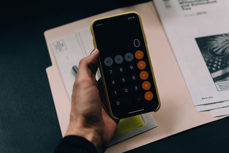 Hand mit Smartphone über Unterlagen und Belegen