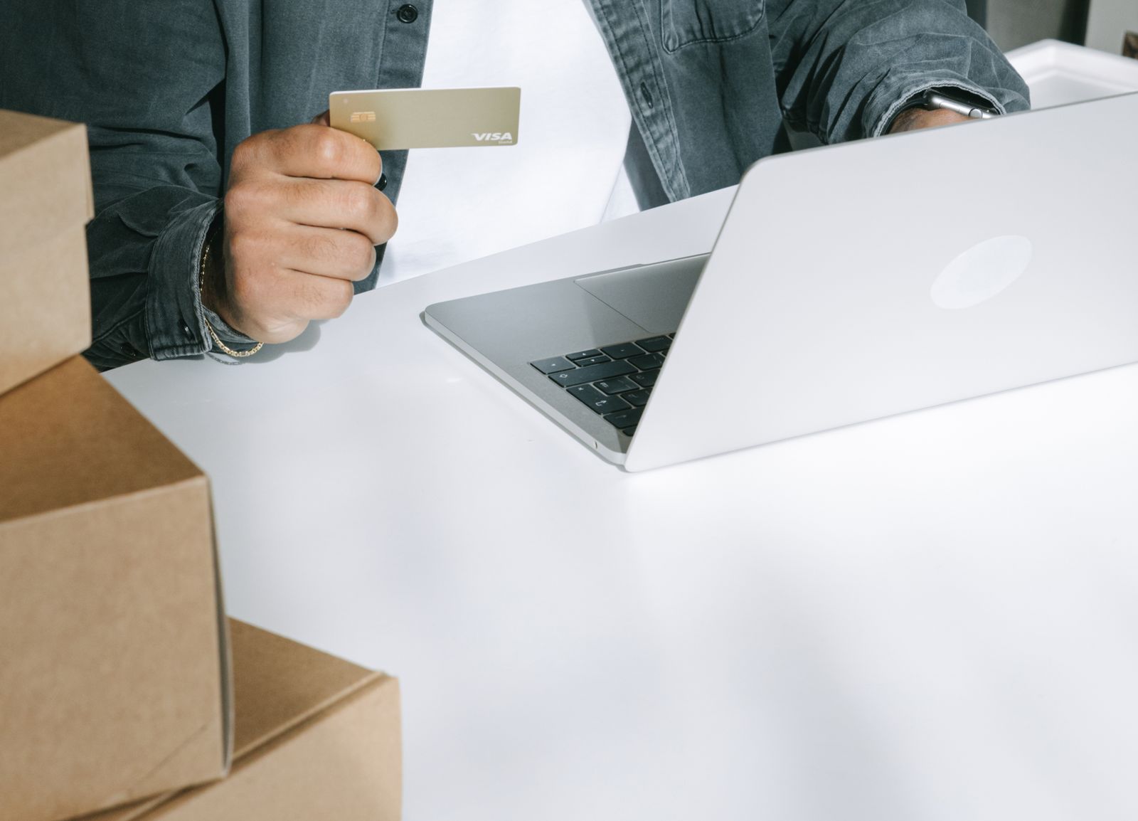 Person kauft mit Kreditkarte an einem Laptop online ein