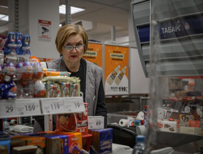 Kassenbereich in einem Supermarkt mit Kundin und Personal
