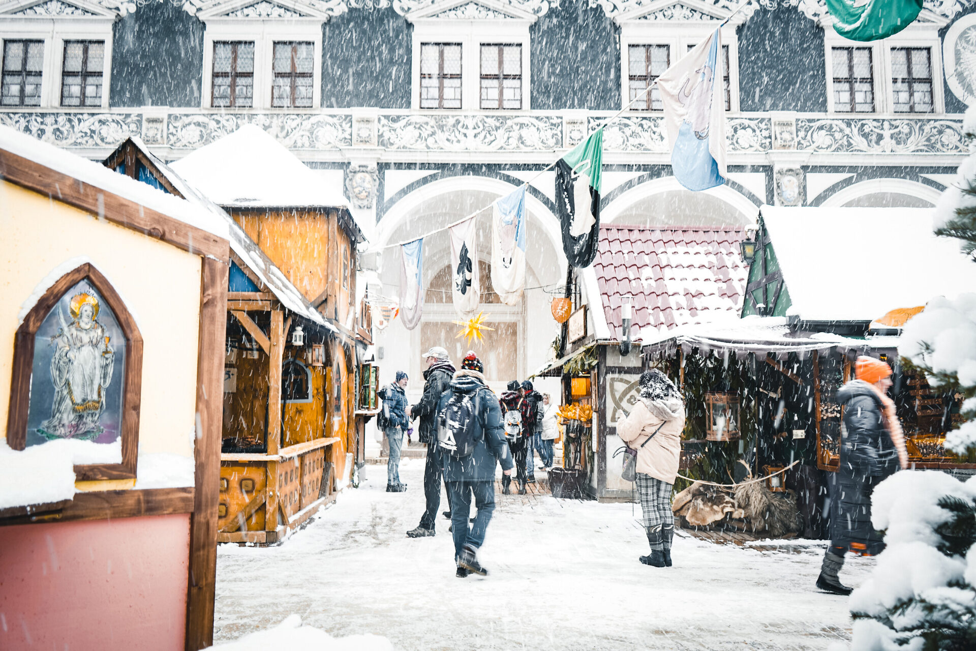 Winterlicher Weihnachtsmarkt im Stallhof Dresden, mit Verkaufsständen und schneebedeckten Menschen.