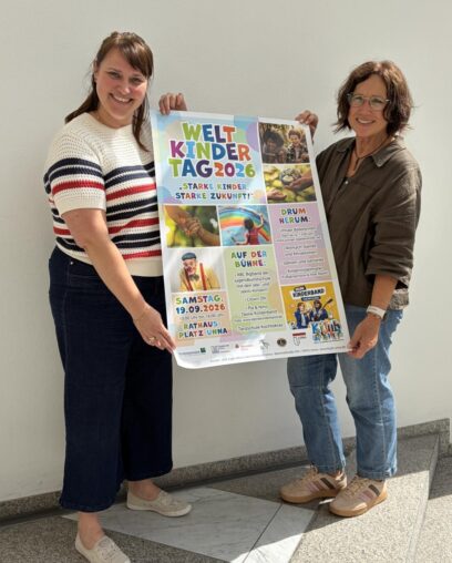 Zwei Mitarbeiterinnen der Kreisstadt Unna zeigen das Plakat zum Weltkindertag 2026