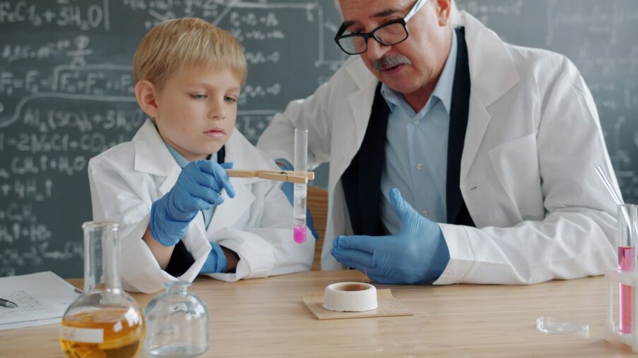 Kind und Lehrkraft bei einem naturwissenschaftlichen Experiment im Unterricht